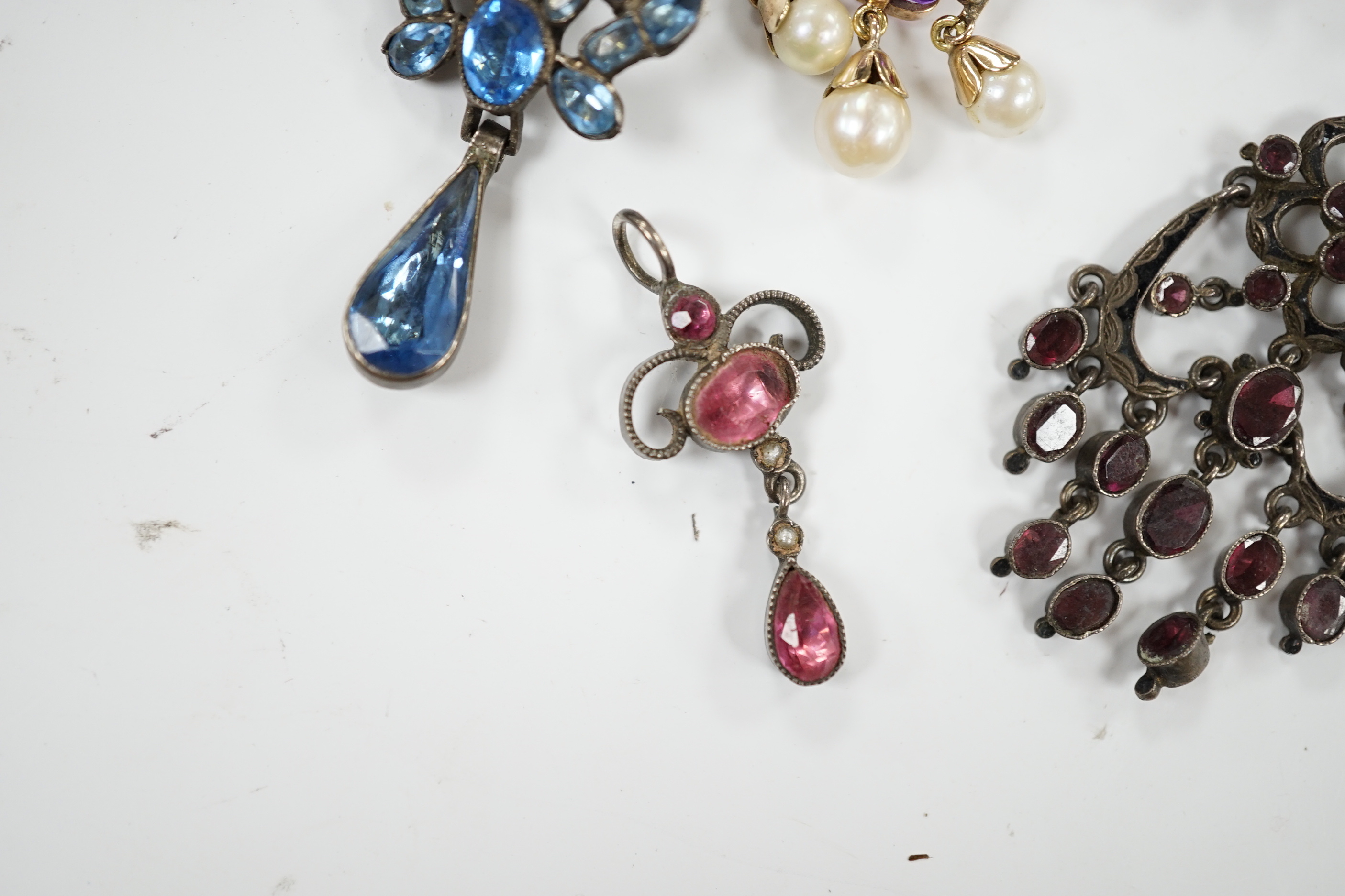 A Georgian yellow metal and foil backed garnet set cluster pendant, 26mm and four other later pendants.